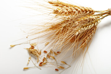 Naklejka premium Wheat stalks lie on a white surface with scattered seeds around them in a simple setup