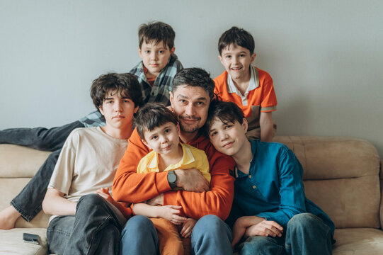 Father sitting on sofa with sons embracing and smiling at home