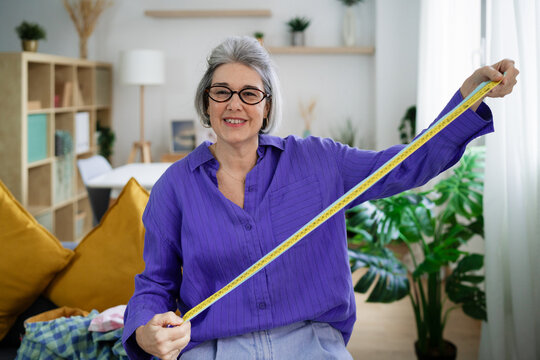 Tailor smiling confidently with measuring tape indoors