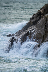 Naklejka premium Vue d'une côte rocheuse où les vagues s'écrasent sur les rochers, illustrant la puissance de la mer.