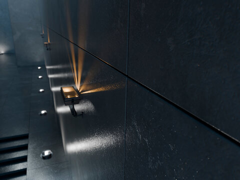 Dark textured wall with modern architectural lighting and strong beams