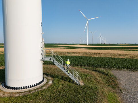 Engineer inspecting wind turbine for renewable energy in rural field