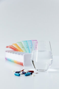 Medication pill box and water glass for daily routine on white table