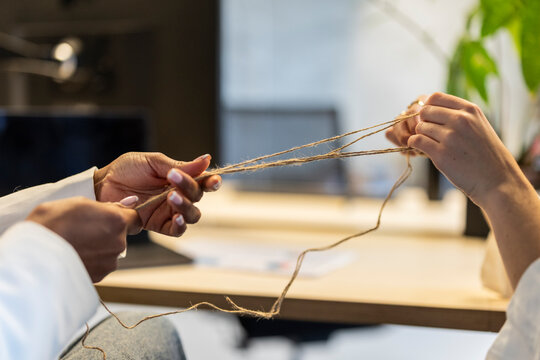Hands collaborating with string representing unity and cooperation indoors