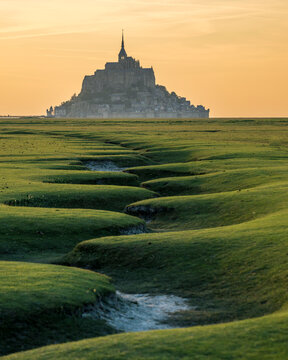 Mont-Saint-Michel abbey and meandering landscape at sunset