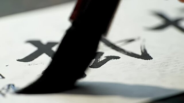 Black ink calligraphy characters on white paper, angled view, shallow depth of field