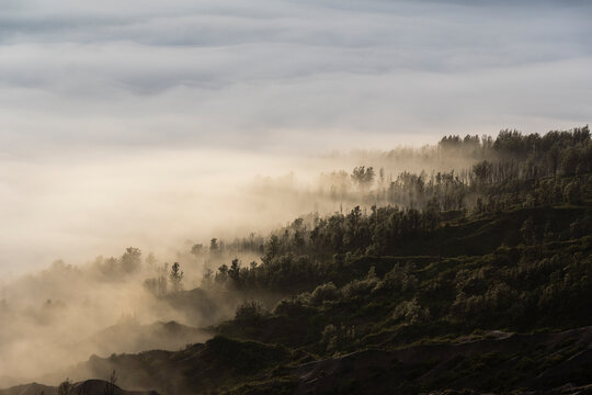 Dreamy foggy sunrise landscape with lush hills in Java Indonesia