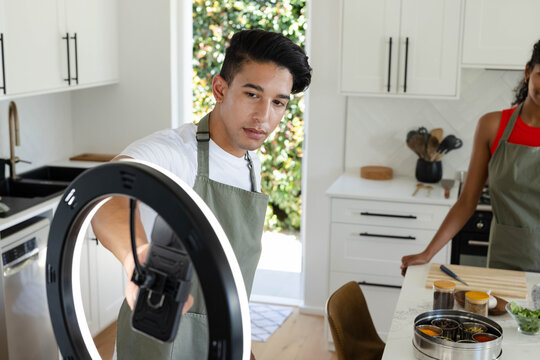 Circular LED light is illuminating phone and counter with spices, board and herbs at window