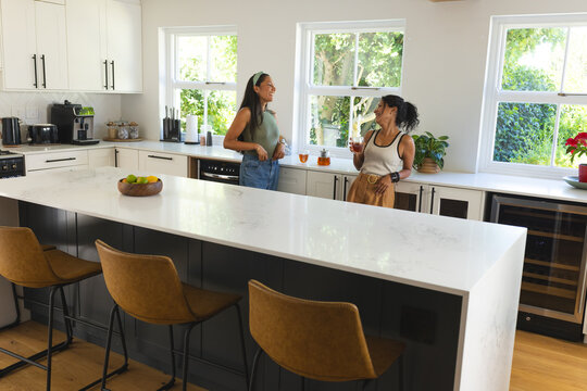 White marble island is anchoring modern kitchen with leather bar stools and citrus bowl