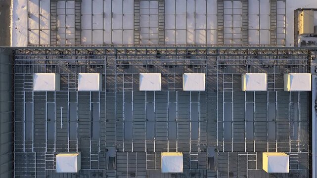 Aerial footage moving over the snow covered rooftop of a modern data center building, showing rows of industrial hvac air conditioning units