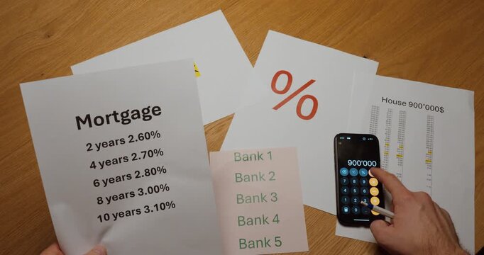 Top view of mortgage documents with different interest rates, bank comparison sheet and smartphone calculator. Concept of home loan selection, financial planning, interest rate comparison, investment