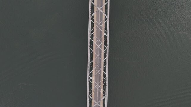 Cinematic top-down drone shot of a car driving across the Adomi Bridge over the Volta River in Akosombo, Ghana. West African infrastructure and river landscape
