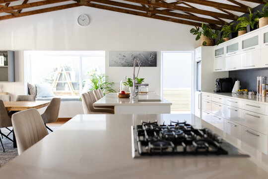 Central kitchen island is gleaming with tall chrome faucet and fruit bowl in open-plan dining area