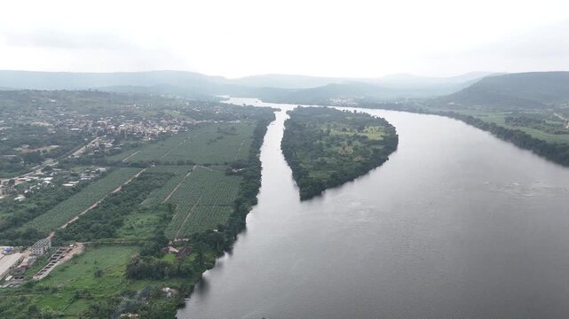 Panoramic drone view of the Volta River and lush tropical hills in Akosombo, Ghana. High-angle perspective of the West African river landscape and dense greenery
