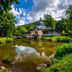 Fototapeta premium Scenic view of a beautiful building with a pond and lush greenery under a cloudy sky.