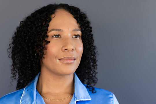 African American woman gazing in gray headshot blue pj top white trim gold-chain and hoop-nose-ring