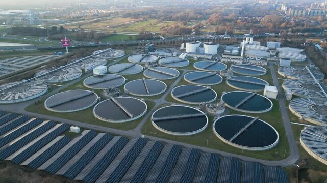 Drone shot of multiple circular clarifier tanks at a large wastewater treatment facility.