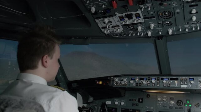 Confident captain in cockpit looks at windshield preparing for departure. Professional pilot in uniform awaits flight in evening