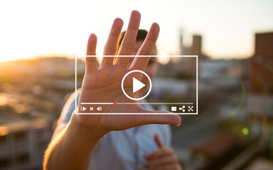 Hand with play button overlay cityscape background hand, play button, cityscape, urban, blurred background, sunset, white outline, media player, pause button, play controls, person, palm, fingers spre