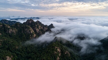 Obraz premium Mountain peaks emerging above sea of clouds at sunrise