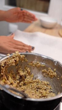 A person is holding a bowl of food in their hand, with a spoon in the bowl. The food appears to be a mixture of oats and bananas, and it looks like it's being prepared for a meal