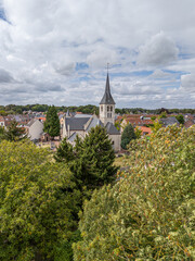 Fototapeta premium Aerial, bird view church of Eppegem village, a small rural village in the countryside of Belgium. deciduous trees in foreground. Houses around the church. Cloudy autumn day. Beautiful rural town. Natu