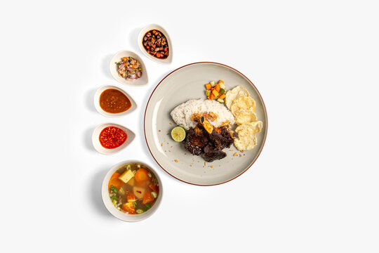 indonesian grilled beef ribs rice set with sambal, soup and condiments isolated on white background. nasi iga bakar