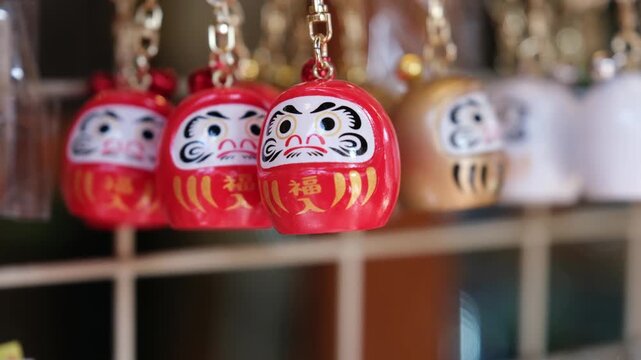 Red Japanese Daruma good luck charm keychains swinging at a souvenir stall in Tokyo