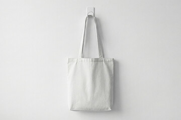 Blank white canvas tote bag hanging on white wall