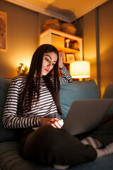 Fototapeta premium Woman serious and pensive while working from home using laptop computer late at night