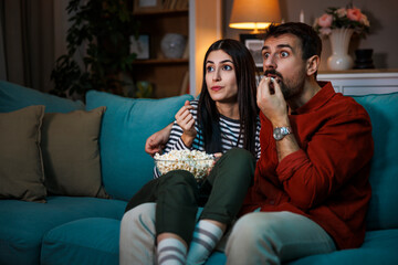 Fototapeta premium Couple watching scary movie on TV at home at night