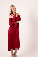 Elegant woman in long red robe standing in studio room