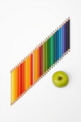 A vibrant spectrum of colored pencils arranged in a rainbow gradient with an apple