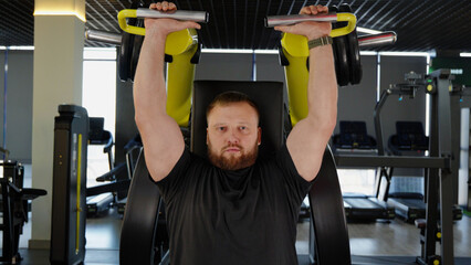 Athletic man performing lat pulldown exercise in modern gym