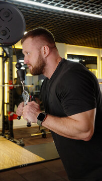 Fit man doing triceps pushdown exercise on cable machine