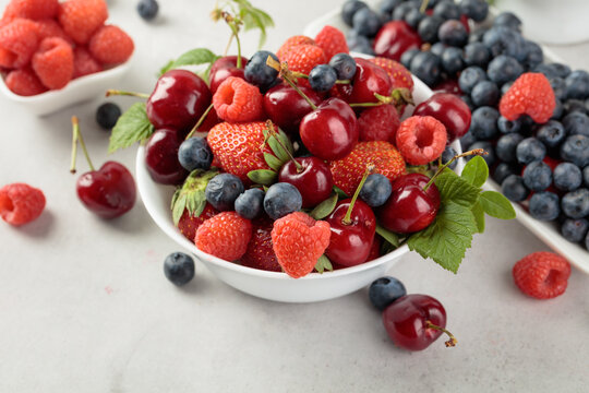 Berries closeup colorful assorted mix of strawberry, blueberry, raspberry and sweet cherry on a white table.