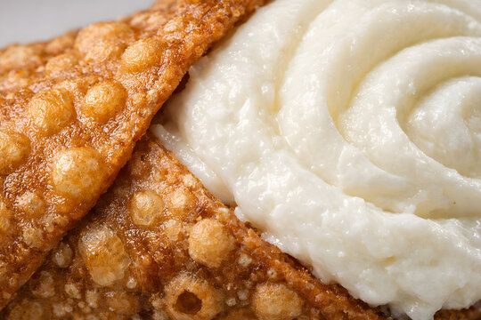 An extreme close up view highlights the crunchy cannoli shell and smooth ricotta cream texture