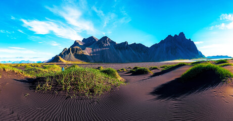 Scenic landscape with most breathtaking mountains Vestrahorn on the Stokksnes peninsula and cozy lagoon with green grass on the sand dunes  in Iceland. Exotic countries. Amazing places. © anko_ter