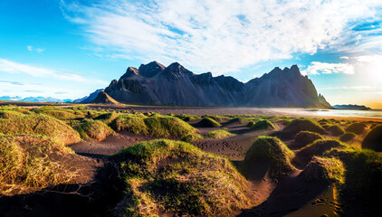 Scenic landscape with most breathtaking mountains Vestrahorn on the Stokksnes peninsula and cozy lagoon with green grass on the sand dunes in Iceland. Exotic countries. Amazing places.