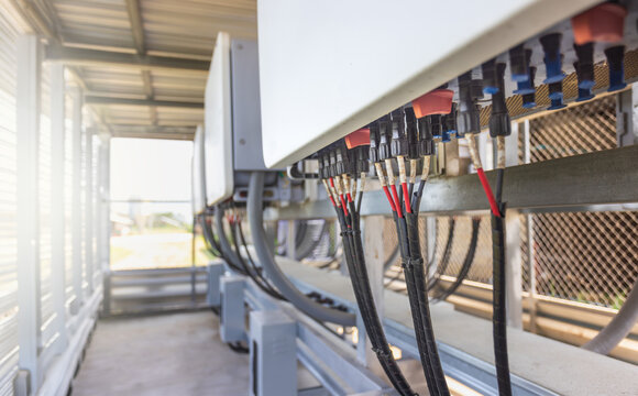 Close-up of MC4 connectors and DC solar cables connected to string inverter in a large scale PV system.