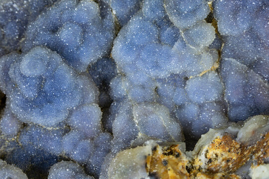 Closeup of blue druzy botryoidal quartz clusters. Host rock matrix in the foreground. 
