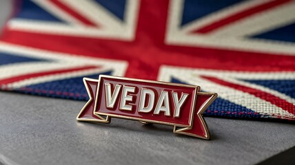 Red and gold ve day pin badge placed over union jack fabric to honor military service and historical peace agreement after conflict with shallow depth of field for elegant focus