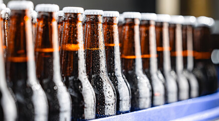 Row of chilled Brown glass beer bottles in modern brewery production line