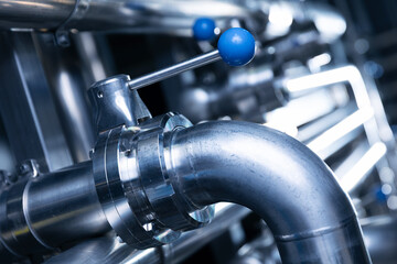Pipes stainless steel brewing equipment, large reservoirs or tanks in modern beer factory. Brewery production concept, industrial blue background