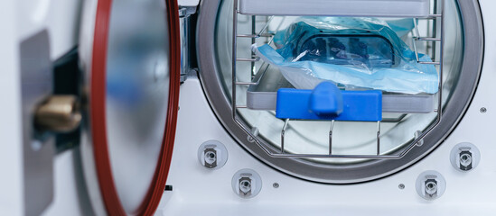 Open dental autoclave chamber with wrapped instrument packs and gasketed door for sterilization...