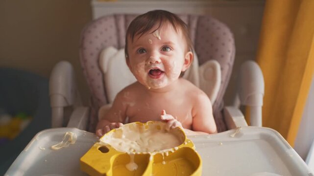 baby eats dirty. happy family a kid toddler concept. baby girl dirty sitting messing with food at the table for feeding in the kitchen lifestyle. grimy toddler in the kitchen