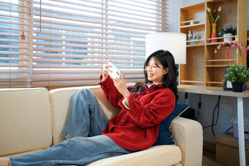 Obraz premium woman user holding smart phone watching video, playing game, shopping, chatting in mobile technology application sitting on sofa at home. Close up view, banner design