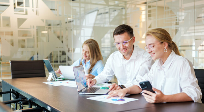 Business team works on project in modern office during the day using laptops and papers