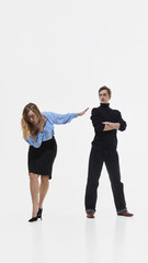 Fototapeta premium Fashionably dressed woman pushing man away in dramatic studio pose on white background. Concept of relationship conflict, gender roles styling and expressive editorial fashion narrative.