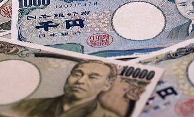 Japanese yen money bills pile on table. Japan banknotes of JPY currency close up. © Larysa
